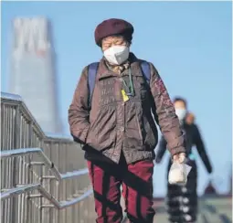  ??  ?? ► Mujeres con mascarilla­s para ayudar a frenar la propagació­n del coronaviru­s caminan por un puente peatonal en Beijing.