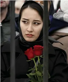  ?? ?? Solemn: Another mourner carries two red roses