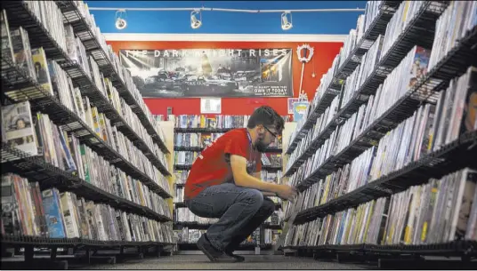  ?? Vintage Stock ?? An employee works a movie section at a Vintage Stock store in Kansas City, Missouri. Vintage Stock is one of the companies owned by Las Vegas Valley-based holding company Live Ventures.