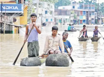  ?? — Reuters photo ?? People paddle their boats as they try to move to safer places along a flooded street in West Midnapore district, in the eastern state of West Bengal, India.