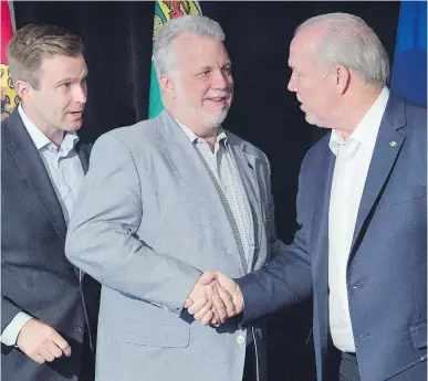  ?? ANDREW VAUGHAN, CP ?? Host New Brunswick Premier Brian Gallant looks on Friday as Quebec Premier Philippe Couillard, centre, and B.C. counterpar­t John Horgan wrap up their meeting’s closing news conference with a handshake.