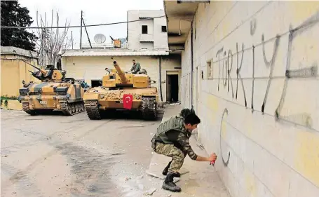 ?? Turecký voják píše sprejem na betonovou zeď nápis „Turecko“v centru dobytého města Afrín na severozápa­dě Sýrie. FOTO ČTK/ AP ??