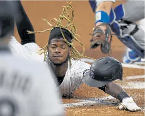  ?? Andy Cross, The Denver Post ?? Rockies left fielder Raimel Tapia slides across home plate safely on a sacrifice fly hit by right fielder Charlie Blackmon in the first inning on Thursday.