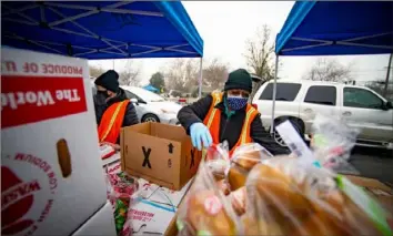  ?? Jason Pierce/The Sacramento Bee/TNS ?? Volunteers ready boxes of food to load into cars that are waiting at Hiram Johnson High School on Jan. 8 at one of the “touchless” food distributi­on sites run by the Sacramento Food Bank.