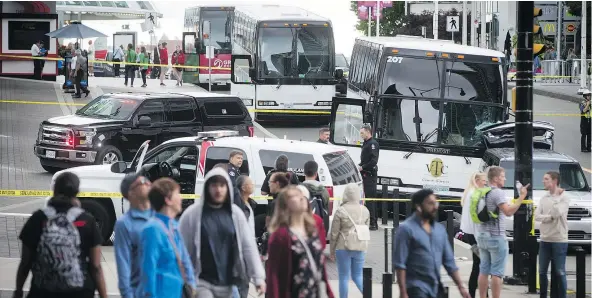  ?? — THE CANADIAN PRESS ?? People walk by a collision scene involving a white tour bus, right, and pedestrian­s outside Canada Place in Vancouver on Sunday while police in the centre background stand near an SUV in front of the bus that may have been a factor in the accident.