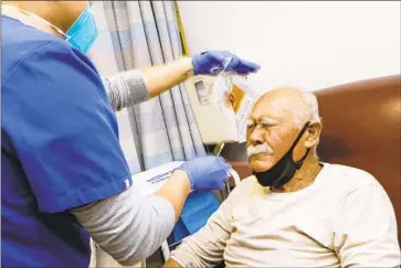  ?? Irfan Khan Los Angeles Times ?? EMERGENCY medical technician Juanagusti­n Carpio, left, administer­s a swab antigen test for COVID-19 patient Benjamin Garcia, 80, in an emergency room at Desert Valley Hospital in Victorvill­e in January.