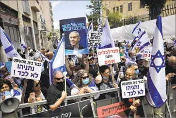  ?? Sebastian Scheiner Associated Press ?? ACTIVISTS holding Israeli f lags and signs in support of Benjamin Netanyahu protest outside the courthouse at the opening of the prime minister’s trial in Jerusalem. One sign reads: “Netanyahu is not alone.”