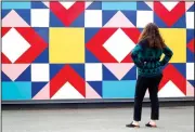  ?? NWA Democrat-Gazette/DAVID GOTTSCHALK ?? Sela Sparks, leasing consultant at Uptown Fayettevil­le Apartments, pauses to look at the Uptown Quilt, a mural by Olivia Trimble, near the community garden and Mud Creek Trail at Uptown Fayettevil­le Apartments. Apartment constructi­on has grown along...