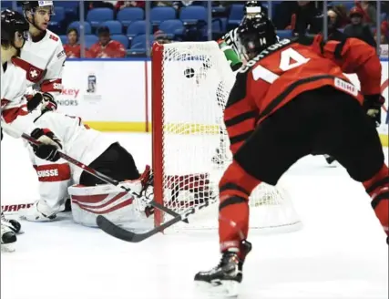  ?? NATHAN DENETTE, THE CANADIAN PRESS ?? Maxime Comtois puts the puck past Swiss goalie Matteo Ritz for Canada’s eighth goal of the game with less than a minute left to go in the third period.