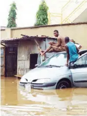  ??  ?? Residents take refuge on a car