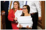  ?? TAMIR KALIFA / AMERICANST­ATESMAN ?? Legislativ­e aides distribute the House budget bill Wednesday before a committee meeting at the Capitol.