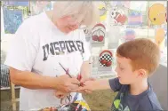  ?? ?? Wells Austin, 5, of Prairie Grove, wanted a car painted on his arm. Artist Sharon Tate of Searcy said she stayed busy all day during the Clotheslin­e Fair painting faces and arms. Her booth was called Sharon’s Paintbrush.