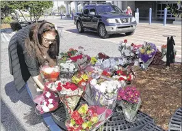  ?? JOHN RAOUX / ASSOCIATED PRESS ?? Shawn Bergquist on Tuesday places a bouquet of flowers at a makeshift memorial in the parking lot of the Wal-Mart where Orlando police officer Debra Clayton was shot and killed. The suspect remains at large.