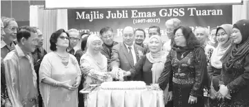  ??  ?? Hajiji (centre) cutting the anniversar­y cake yesterday.