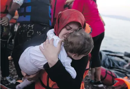  ?? PETROS GIANNAKOUR­IS/THE ASSOCIATED PRESS ?? A Syrian woman and her child arrive on the Greek island of Lesbos from Turkey on Saturday. The Conservati­ve government says Syrians fleeing conflict will be presumed to be refugees by Canadian authoritie­s for the purposes of vetting their applicatio­ns.