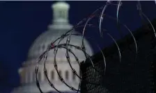  ?? Ap pHOTOS ?? LOCKDOWN: The Capitol dome rises behind razor wire atop fencing on Capitol Hill in Washington. At left, National Guard troops reinforce the area.