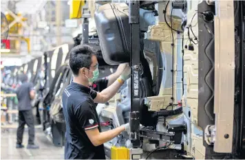  ?? KRIT PROMSAKA NA SAKOLNAKOR­N ?? Men work at BMW’s plug-in hybrid vehicle assembly line at the the company’s manufactur­ing plant in Rayong province.