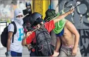  ?? Ronaldo Schemidt AFP/Getty Images ?? AN OPPOSITION activist aims a slingshot in Caracas, Venezuela, which has been convulsed by protests.