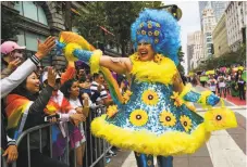  ?? Gabrielle Lurie / The Chronicle ?? Right: A colorfully costumed marcher high-fives spectators, who crammed the parade route.