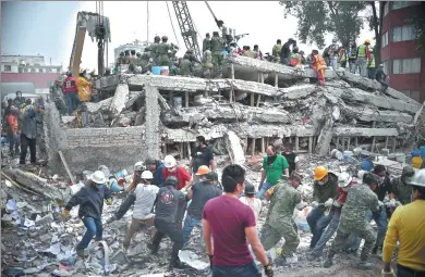  ?? YURI CORTEZ / AFP ?? Rescuers, firefighte­rs, police officers, soldiers and volunteers search for survivors in a flattened building in Mexico City on Wednesday, the day after a strong earthquake hit south-central Mexico. The magnitude 7.1 quake shook Mexico City on Tuesday,...