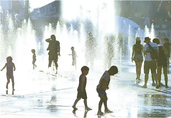  ??  ?? Children play in the water fountains at the Place des Arts in Montreal, Canada on a hot summer day.