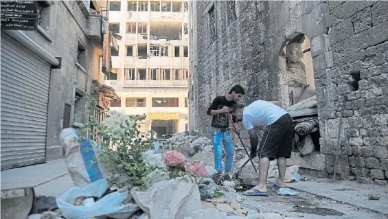  ?? DPA ?? Escombros. Dos habitantes limpian una calle en Aleppo, mientras cientos de familias buscan volver a sus casas tras la huida de los yihadistas.