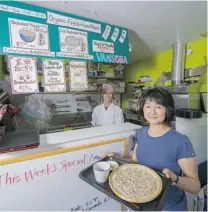  ?? MIA STAINSBY/ VANCOUVER SUN ?? Hiroko Sugiyama holds a cold buckwheat noodle dish cooked by Takashi Koriyama, background, at Tama Organic Life alongside Ethical Kitchen in North Vancouver.