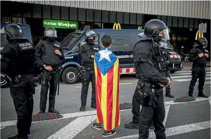  ?? PHOTO: AP ?? A demonstrat­or wrapped in a Catalan independen­ce flag faces off with police during a protest in Barcelona condemning the arrest of Catalonia’s former president, Carles Puigdemont, and the jailing of Catalan politician­s on sedition charges.