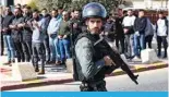  ?? ?? A member of the Zionist security forces walks past Palestinia­n Muslims performing the Friday noon prayer on a street blocked by them in the east Jerusalem neighborho­od of Ras al-Amud.