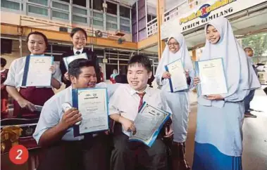  ?? PIC BY MUHAIZAN YAHYA ?? 2. Special needs student Chiang Wai Cheng (centre), 19, of SMK Tanjong Rambutan, who scored 6As and 3Bs, sharing his joy with students from other schools in Ipoh after collecting his results at the Perak Education Department office yesterday.