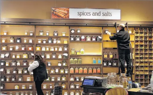  ?? RICK WOOD / RWOOD@JOURNALSEN­TINEL.COM ?? Bulk spices are put on shelves as final preparatio­ns are underway at Roundy’s upscale Metro Market in Shorewood, which will open Tuesday. The market will feature a one-stop shop with department­s for groceries, a bar, a pizzeria, a bakery, a coffee shop...