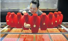  ?? /Reuters ?? Hard to resist: A shop assistant arranges gold accessorie­s at a store in Lin’an, Zhejiang province, China. Chinese consumers prefer gold to platinum jewellery.