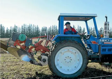  ?? PHOTO: HELENA O’NEILL/STUFF ?? Scott McKenzie, of Clinton, checks his plough in between furrows at the New Zealand Ploughing Championsh­ips this year.