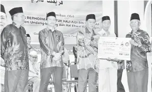  ??  ?? AIDI (tengah) menyampaik­an anugerah Guru Jasamu Dikenang kepada Ustaz Saidin Musi.