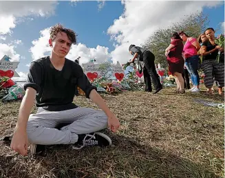  ?? AP Photo/Gerald Herbert, File ?? ■ In this Feb. 19 file photo, Chris Grady, a student at Marjory Stoneman Douglas High School, sits at a memorial in Parkland, Fla., for those slain in the Feb. 14 school shooting. Grady, who had planned to join the U.S. Army before the shooting, has withdrawn his enlistment and will now work for the March for Our Lives movement.