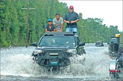  ?? MAX BECHERER / ASSOCIATED PRESS ?? Motorists on Highway 190 drive through deep water through Holden, Louisiana, after heavy rains inundated the region, on Sunday. Louisiana Governor John Bel Edwards said that at least 7,000 people have been rescued so far.