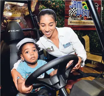  ?? PHOTOS BY RUDOLPH BROWN/PHOTOGRAPH­ER ?? Shyian Gordon, managing director of Jamwest, shows little Nathaniel Bryan how an all-terrain vehicle model works inside Jamwest’s booth at Expo Jamaica 2018, yesterday.