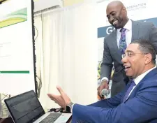  ?? FILE ?? Prime Minister Andrew Holness (sitting) and Dr Andrew Wheatley, then minister of science, energy and technology, launch the GOJ e-portal gov.jm, which became the Government of Jamaica’s online gateway to all government informatio­n and services on August 9, 2017. Wheatley was stripped of the energy portfolio last month and later resigned altogether.