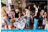  ??  ?? HONG KONG: A vendor (2nd left) at a newsstand sells copies of the Apple Daily newspaper in Hong Kong yesterday, a day after authoritie­s conducted a search of the newspaper’s headquarte­rs.— AFP