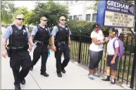  ?? M. Spencer Green / Associated Press ?? Chicago Police patrol the neighborho­od as Crystal Stoval delivers her niece Kayla Porter from their south side home to Gresham Elementary School on the first day of classes in August 2013 in Chicago. Chicago Public Schools closed about 50 schools and programs that year.