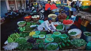  ?? AP ?? Price pressure A roadside vendor arranges vegetables in Ahmadabad. Running a higher deficit could antagonise the Reserve Bank, which is counting on Jaitley’s pledge of tight fiscal policy to keep inflation to 5 per cent by March 2017.