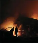  ??  ?? In this Dec. 7, 2017 file photo, two firefighte­rs watch as a home burns in a wildfire in La Conchita. AP PHOTO/JAE C. HONG