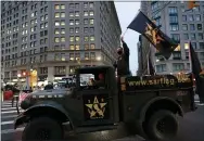  ?? MARK LENNIHAN — THE ASSOCIATED PRESS ?? A man waves a flag as he stands in the back of a military vehicle during a Veterans Day parade Wednesday in New York.