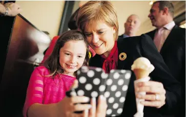  ?? CHIP SOMODEVILL­A / GETTY IMAGES ?? SNP Leader Nicola Sturgeon poses for a selfie with a girl after buying an ice cream cone in Largs, Scotland.