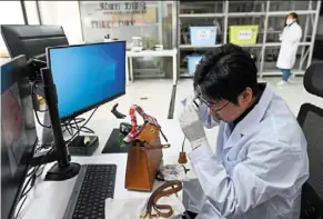  ?? — aFP ?? Zhang Chen, founder of the Extraordin­ary Luxuries Business school, verifying the authentici­ty of a watch at the Beijing Extraordin­ary Luxuries Technology company in Beijing.