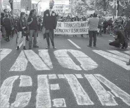  ?? VIRGINIA MAYO, THE ASSOCIATED PRESS ?? Demonstrat­ors walk over a spray painted sign on the street during a demonstrat­ion against internatio­nal trade agreements in Brussels on Sept. 20. The Belgian province of Wallonia is proving how difficult it is for the European Union to set policy for...