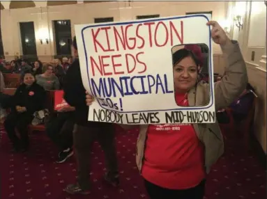  ?? ARIEL ZANGLA — DAILY FREEMAN ?? Diana Lopez of Kingston, the Ulster County coordinato­r for the immigrant rights group Nobody Leaves Mid-Hudson, looks through a sign Tuesday evening at Kingston City Hall that was designed to look like a municipal ID card.