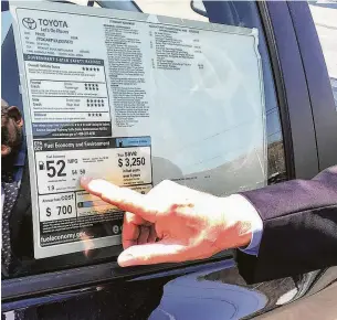  ?? Chris Bosak / Hearst Connecticu­t Media ?? A Toyota dealer points out the fuel efficiency of a Prius on his lot. Sharply higher fuel efficiency rules would likely mean losses for refiners.