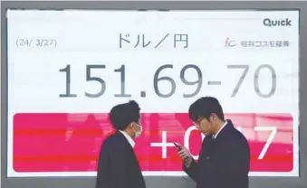  ?? ?? Pedestrian­s walking in front of an electronic board showing the rate of the Japanese yen versus the US dollar on a street in Tokyo yesterday. – AFPPIC