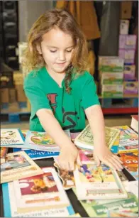  ?? FILE PHOTO ?? Cadence Warren, now 6, arranges books in this file photo of the Choctaw Food Bank. Children who come through the food bank can choose books to take home. The Hunger Run 5K race/walk, scheduled for March 25, will benefit the Choctaw Food Bank and Van...